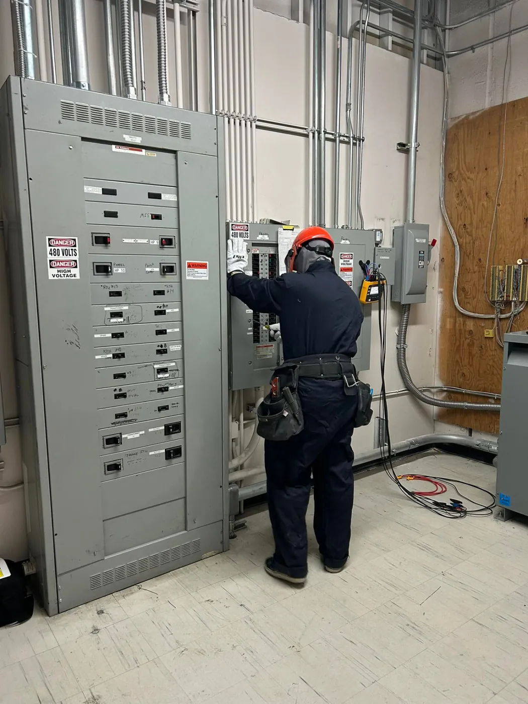 Electrician troubleshooting a 480V commercial electrical panel with a meter