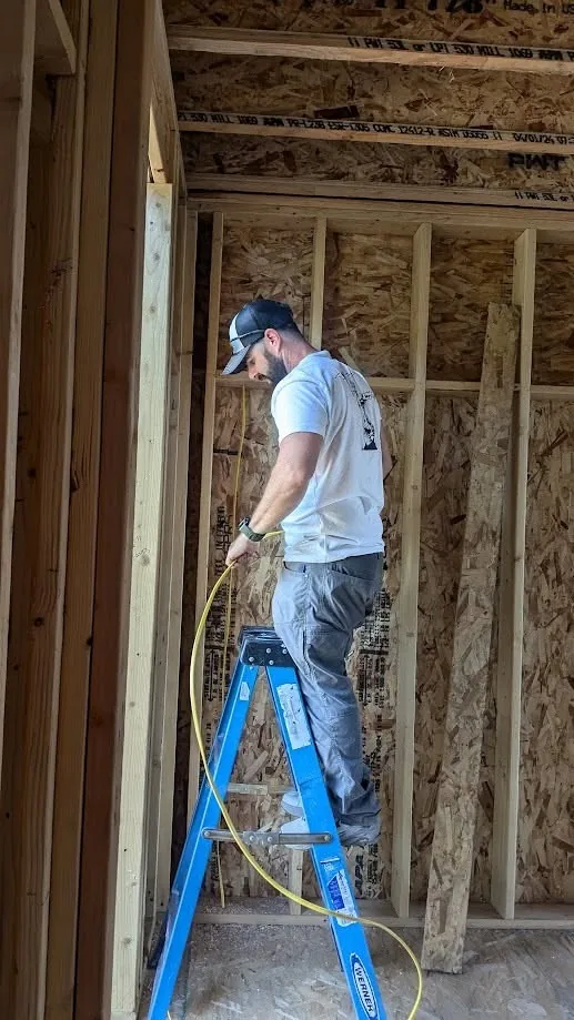 Tactical electrician pulling new wiring through open framing during a whole-home rewire Tactical electrician pulling new wiring through open framing during a whole-home rewire